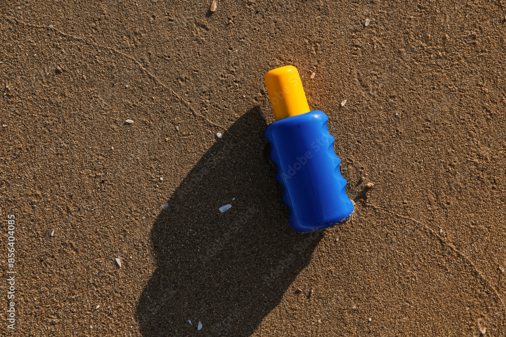 Bottle of sunscreen cream on sand at sea beach Bottle of sunscreen cream on sand at sea beach