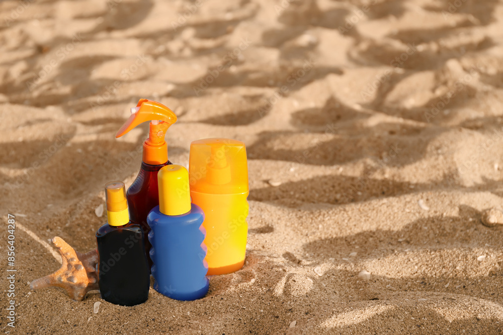 Bottles of sunscreen cream with starfish on sand at beach