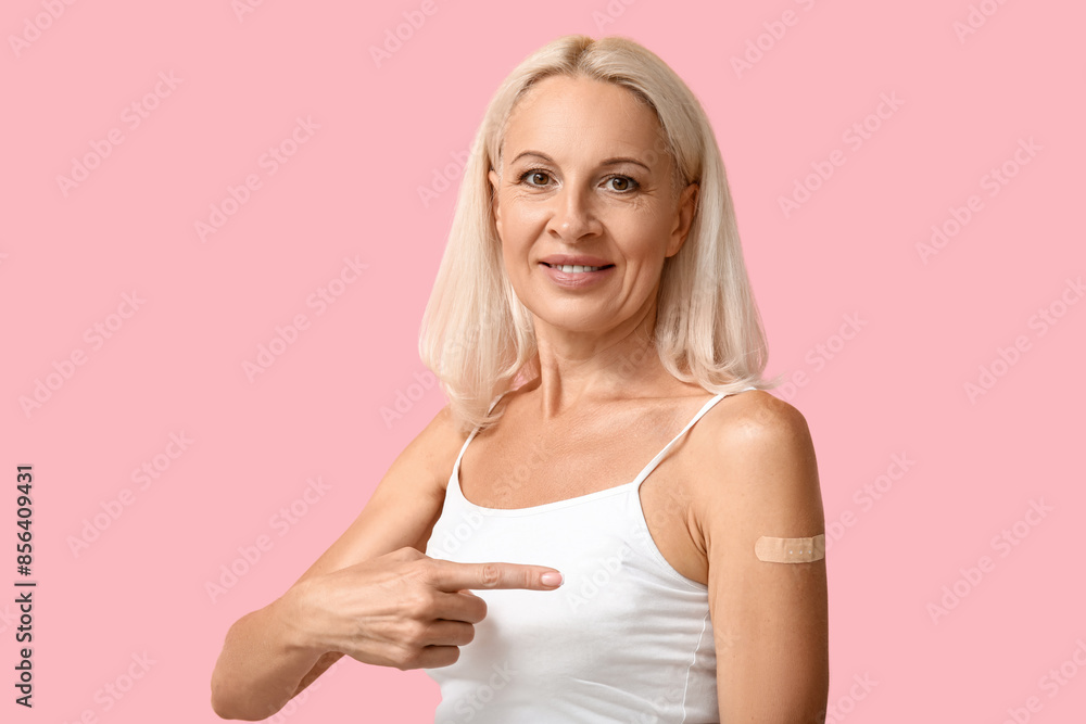Mature woman with medical patch on arm against pink background. Vaccination concept Mature woman with medical patch on arm against pink background. Vaccination concept