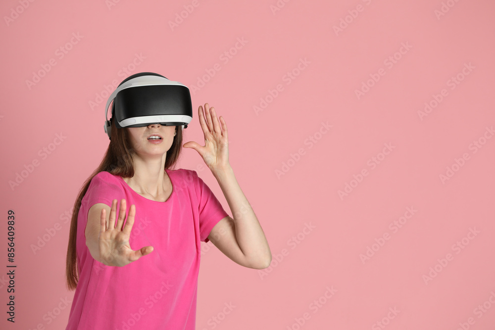Surprised woman using virtual reality headset on pink background, space for text Surprised woman using virtual reality headset on pink background, space for text