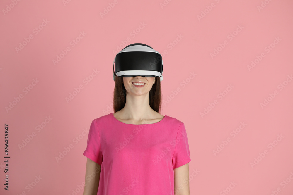Smiling woman using virtual reality headset on pink background Smiling woman using virtual reality headset on pink background