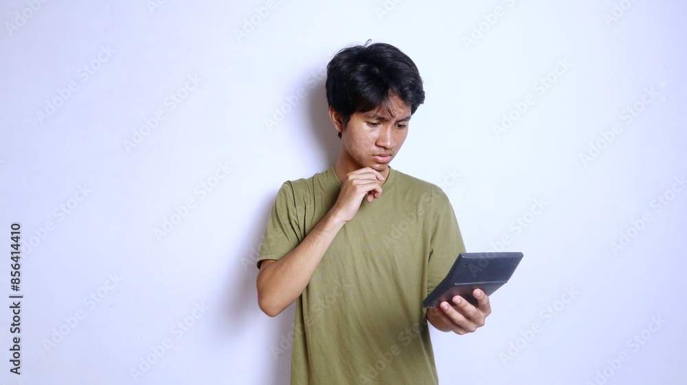 young asian man confused expression and thinking gesture holding and looking at calculator young asian man confused expression and thinking gesture holding and looking at calculator