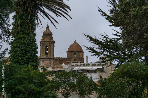 Medieval townscape with bell tower of church of San Giuliano on a sunny day with green trees, Erice, Sicily, Italy