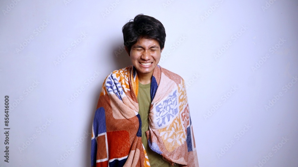 young asian man wearing blanket gesturing sick with flu, fever, chills young asian man wearing blanket gesturing sick with flu, fever, chills