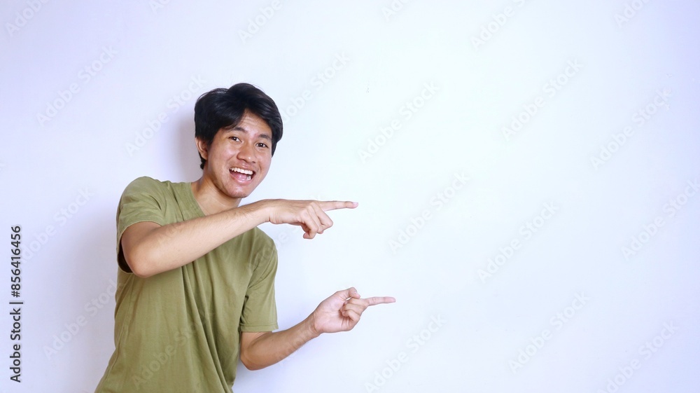 excited young asian man pointing to the side on isolated white background excited young asian man pointing to the side on isolated white background