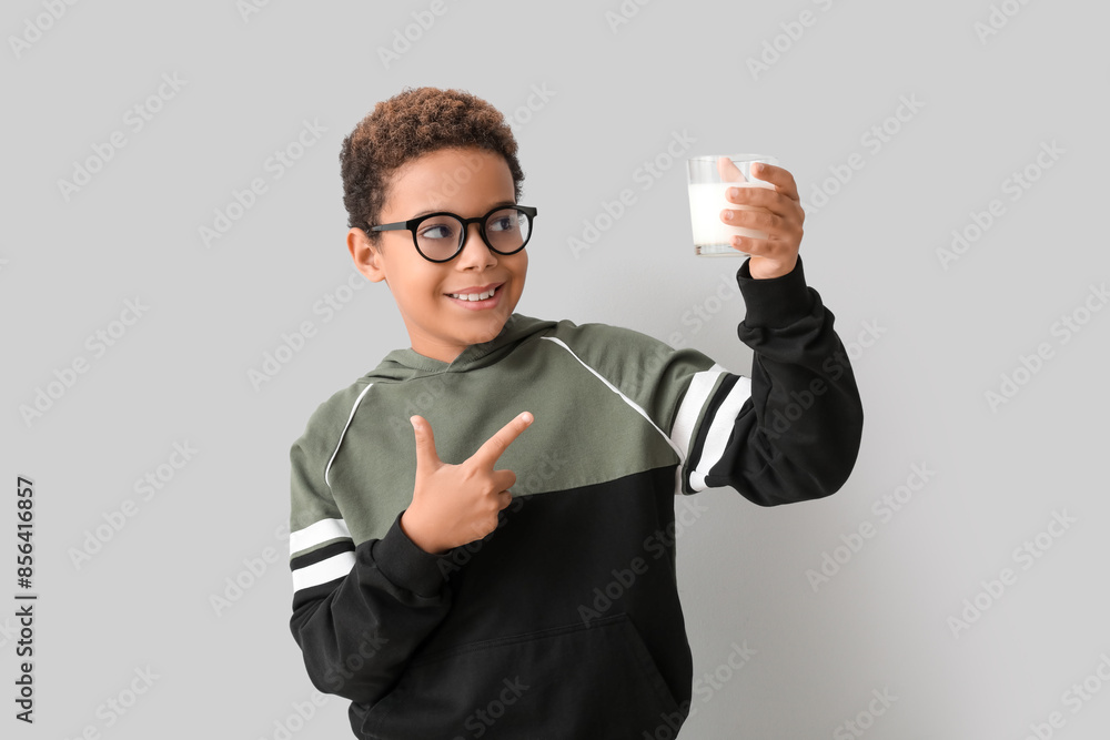 Little African-American boy pointing at glass of milk on white background Little African-American boy pointing at glass of milk on white background