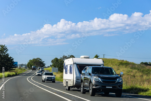 Car towing caravan on road trip through countryside on sunny day photo