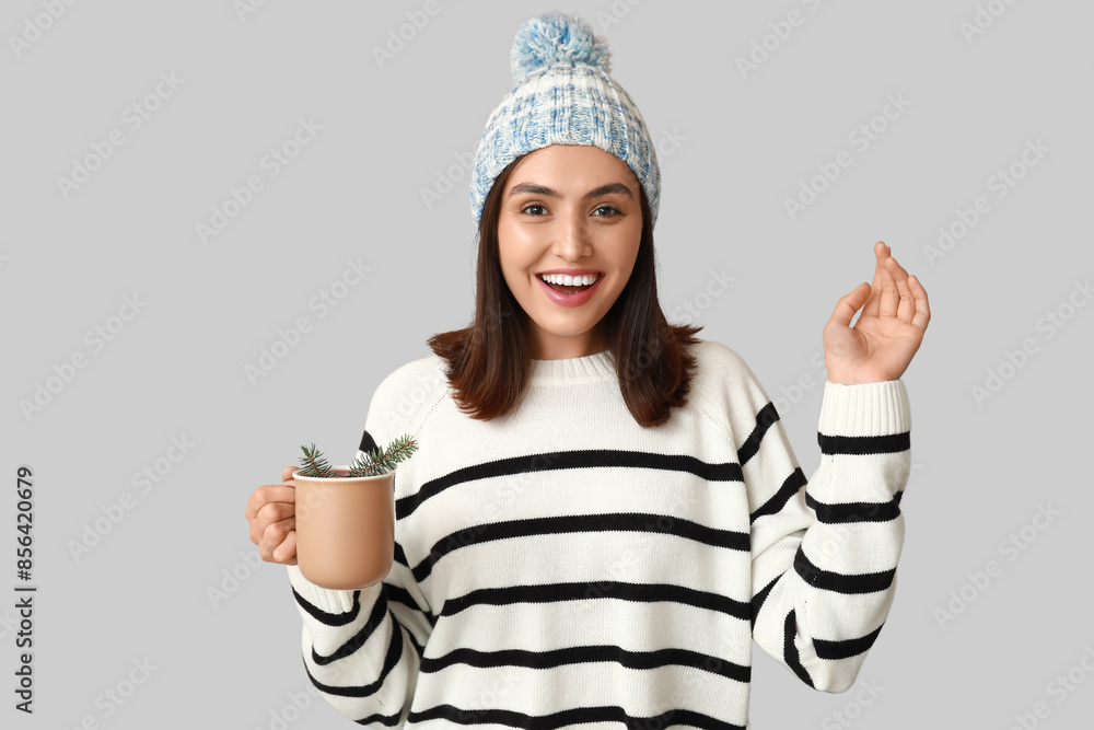 Happy young woman with cup of hot mulled wine on grey background Happy young woman with cup of hot mulled wine on grey background
