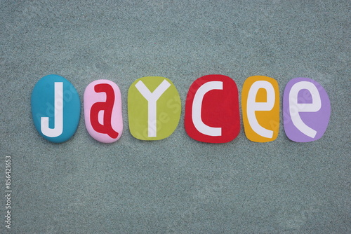 Jaycee, feminine given name composed with hand painted multi colored stone letters over green sand