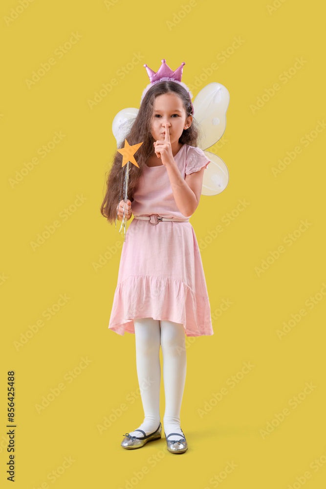 Cute little fairy with wand showing silence gesture on yellow background Cute little fairy with wand showing silence gesture on yellow background