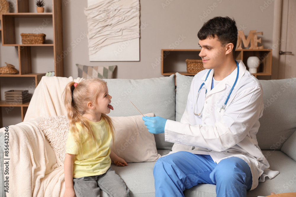Fototapeta premium Male pediatrician examining little girl with tongue depressor at home