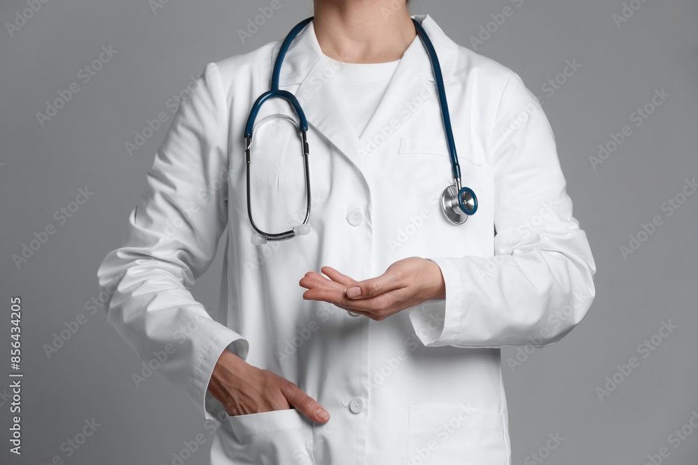 Doctor holding something on grey background, closeup Doctor holding something on grey background, closeup