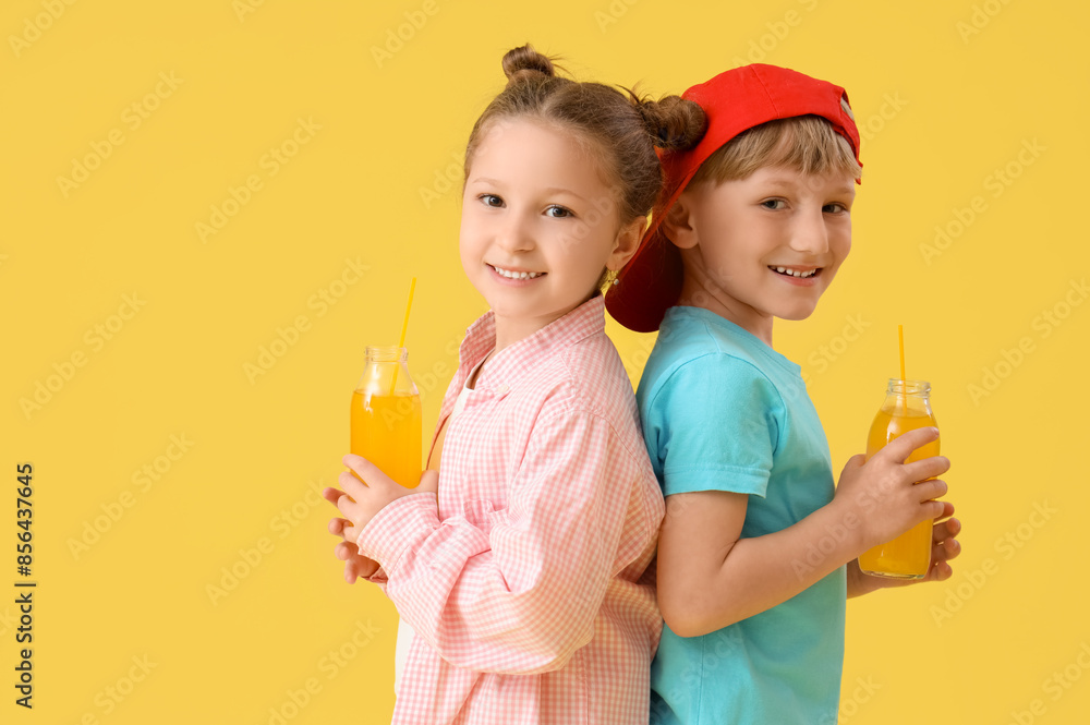 Cute children with bottles of lemonade on yellow background Cute children with bottles of lemonade on yellow background