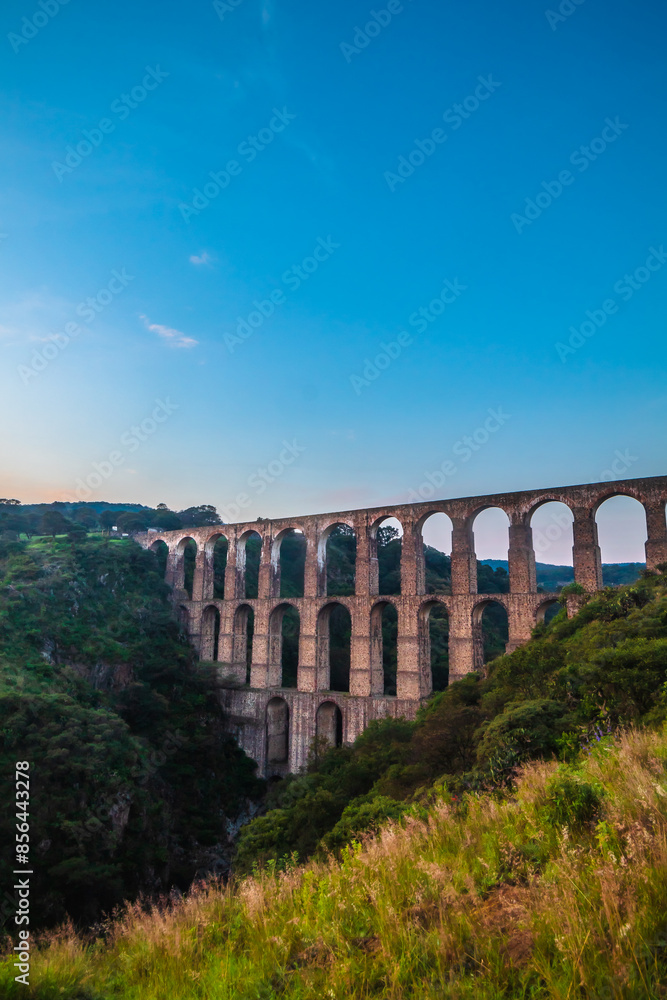 Aqueduct between mountains at sunrise with cloudy sky in arcos del sitio in tepotzotlan state of mexico Aqueduct between mountains at sunrise with cloudy sky in arcos del sitio in tepotzotlan state of mexico