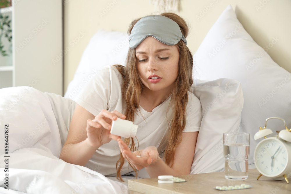 Young woman taking sleeping pills in bedroom Young woman taking sleeping pills in bedroom