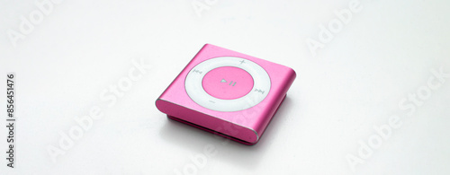 Saint-Petersburg, Russia - May 9, 2022: Pink small metal square old music player iPod Shuffle with big round button on white background close up. Vintage, technique, technology, song, sing. Copy space photo