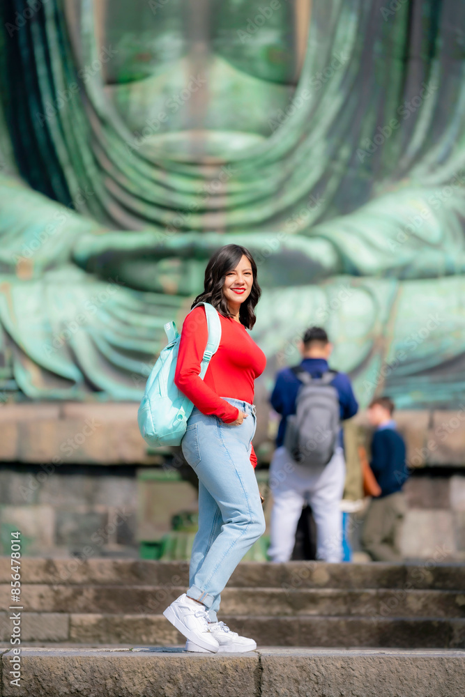A happy young Latina woman standing in front of the Buddha statue at Kotoku-in Temple, Kamakura, Japan. A happy young Latina woman standing in front of the Buddha statue at Kotoku-in Temple, Kamakura, Japan.