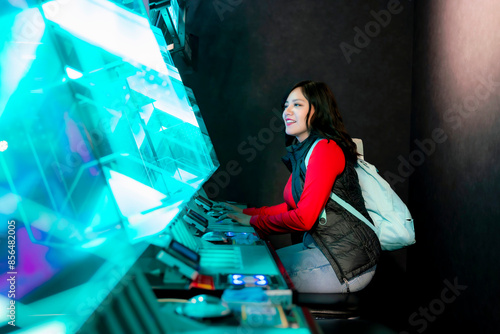 Photography A young Latina woman smiling while playing arcade games in Akihabara, Tokyo, Japan, with glowing futuristic screens