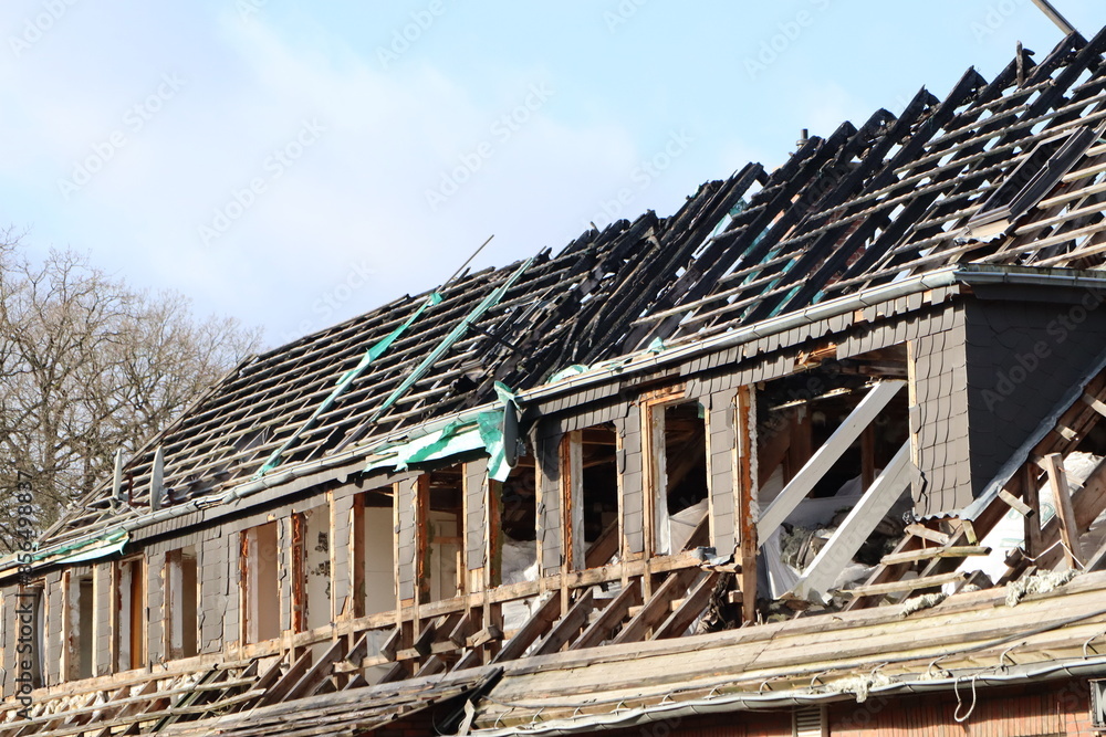 A building is being partially demolished under a clear blue sky, revealing its structural framework