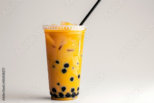 A tall plastic cup of boba tea with a black straw sitting on a white background  photo