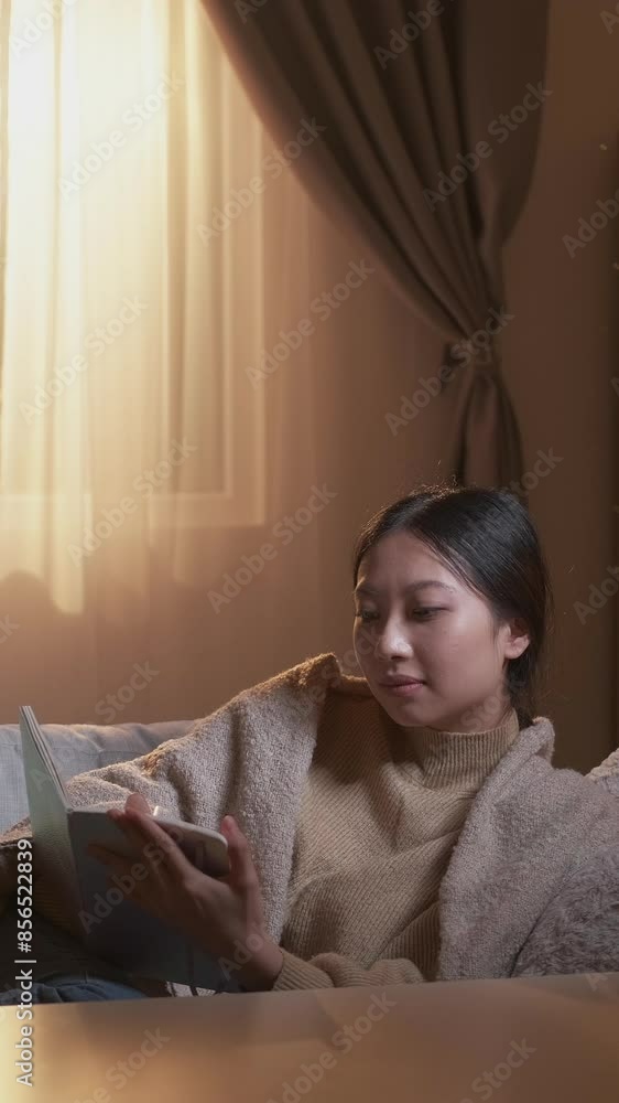 Vertical video. Writing hobby. Weekend leisure. Positive memories. Relaxed inspired woman taking notes in journal on cozy couch in room interior. Vertical video. Writing hobby. Weekend leisure. Positive memories. Relaxed inspired woman taking notes in journal on cozy couch in room interior.