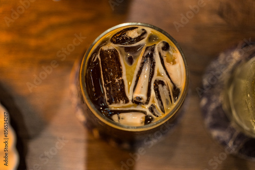 Top view of ice black coffee or Americano on wood table, night club atmosphere