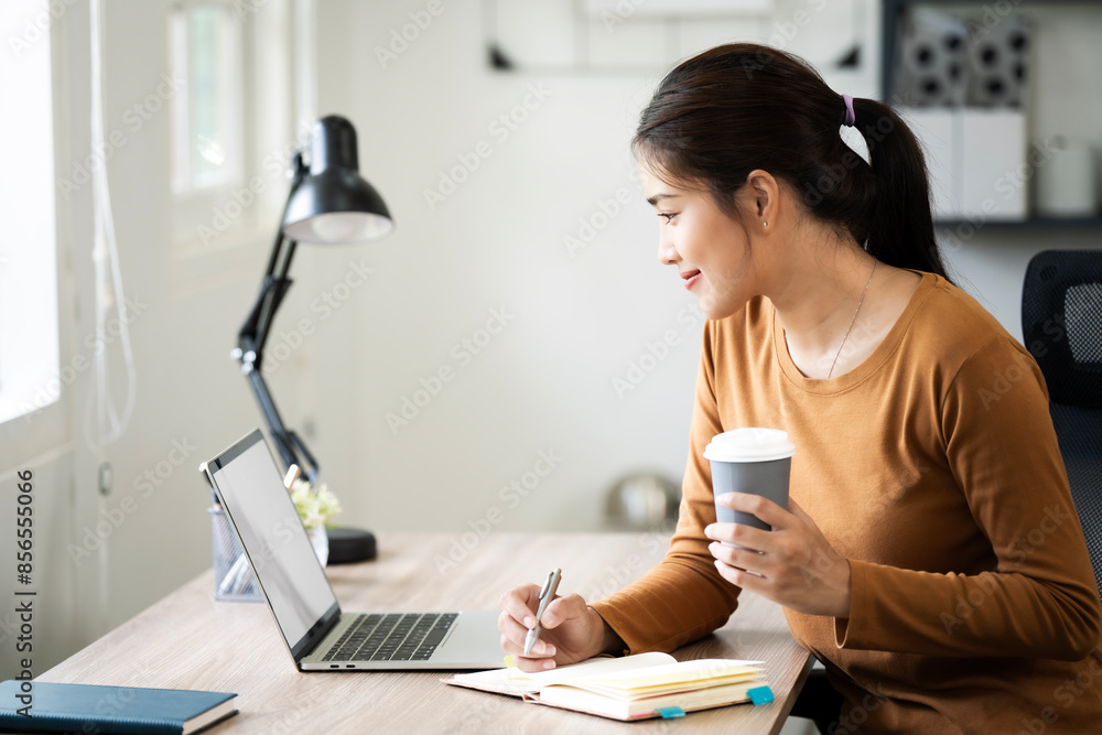 Young happy professional business woman employee sitting at desk working on laptop in modern home office interior. Young happy professional business woman employee sitting at desk working on laptop in modern home office interior.