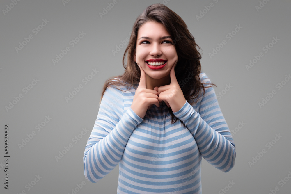 Young woman making funny face and touching cheeks with fingers Young woman making funny face and touching cheeks with fingers