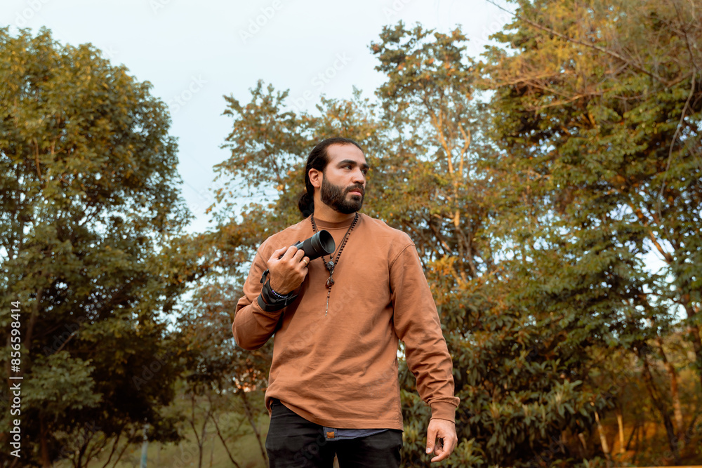 Long-haired, bearded Latino man in a brown jacket documenting his holiday and enjoying the golden hour in his country. World photography and travel day. Long-haired, bearded Latino man in a brown jacket documenting his holiday and enjoying the golden hour in his country. World photography and travel day.