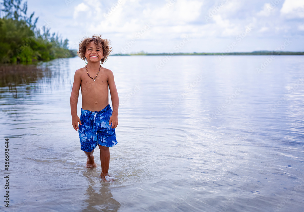 Handsome, smiling, African American boy walking along an ocean lagoon in Florida, Enjoying a fun day in the water Handsome, smiling, African American boy walking along an ocean lagoon in Florida, Enjoying a fun day in the water