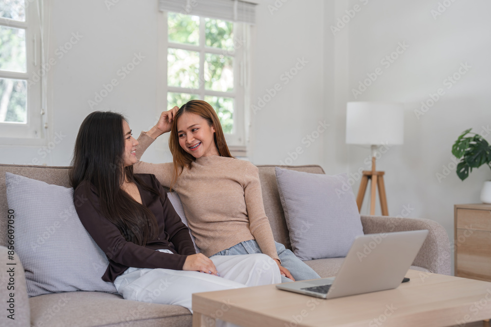Happy Lesbian Couple Sitting Together on a Cozy Sofa in a Modern Living Room, Enjoying Quality Time and Smiling at Each Other Happy Lesbian Couple Sitting Together on a Cozy Sofa in a Modern Living Room, Enjoying Quality Time and Smiling at Each Other