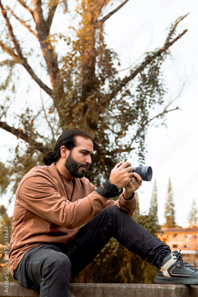 Long-haired, bearded Latino man in a brown jacket documenting his holiday and enjoying the golden hour in his country. World photography and travel day. Long-haired, bearded Latino man in a brown jacket documenting his holiday and enjoying the golden hour in his country. World photography and travel day.