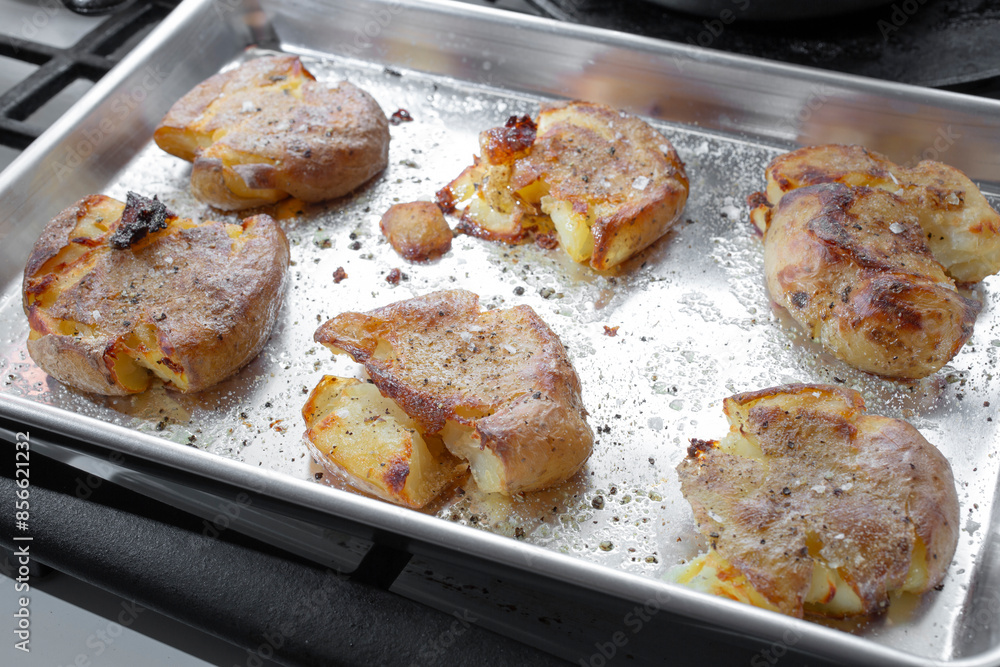 A view of a baking tray of smashed potatoes. A view of a baking tray of smashed potatoes.