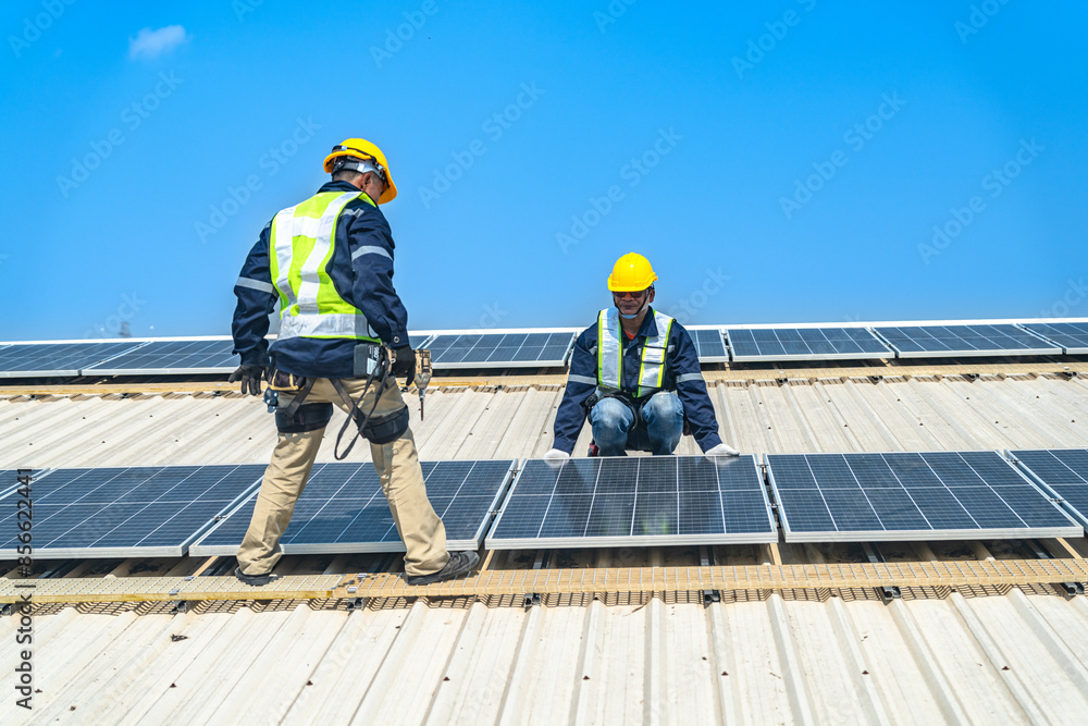 Worker Technicians are working to construct solar panels system on roof with sky and clound on background. Installing solar photovoltaic panel system. Renewable clean energy technology concept. Worker Technicians are working to construct solar panels system on roof with sky and clound on background. Installing solar photovoltaic panel system. Renewable clean energy technology concept.