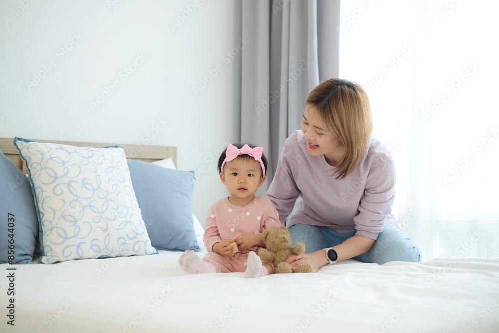 Cute smiling little girl playing with toys on the bed with her mother who cares and teases her. Cute smiling little girl playing with toys on the bed with her mother who cares and teases her.