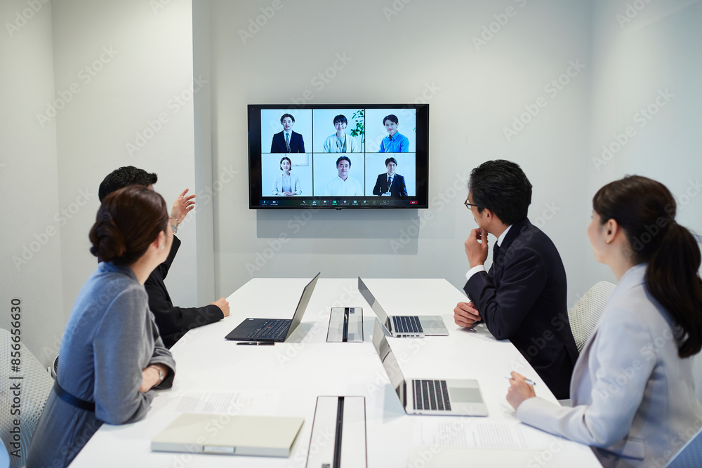 オフィスでオンライン会議をするビジネスマンとビジネスウーマン オフィスでオンライン会議をするビジネスマンとビジネスウーマン