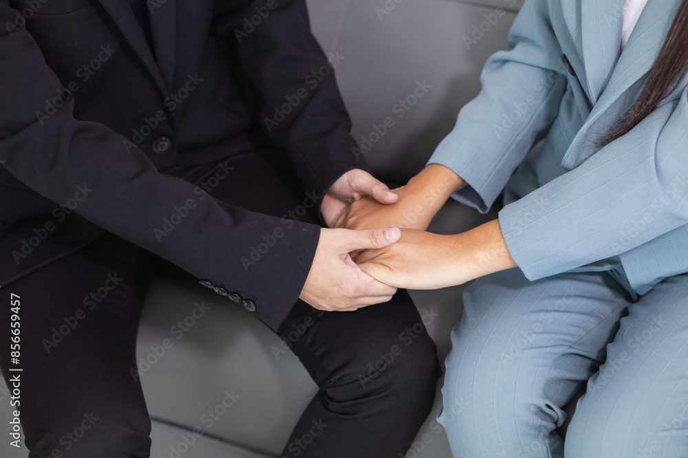 Obraz premium The secretary holds the manager's hand to comfort him during a work problem and resolves it with determination. Concept of friendship, love and understanding between manager and young secretary.