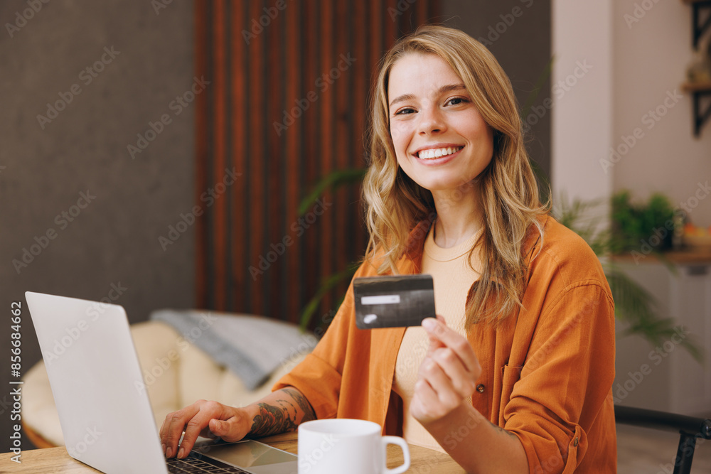Young woman wear shirt use laptop pc computer hold credit bank card shopping online sitting alone at table in coffee shop cafe relax rest at restaurant inside Freelance mobile office business concept Young woman wear shirt use laptop pc computer hold credit bank card shopping online sitting alone at table in coffee shop cafe relax rest at restaurant inside Freelance mobile office business concept
