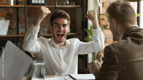 Excited young businessman celebrating success, modern office setting, achievement and motivation, energetic and joyful reaction