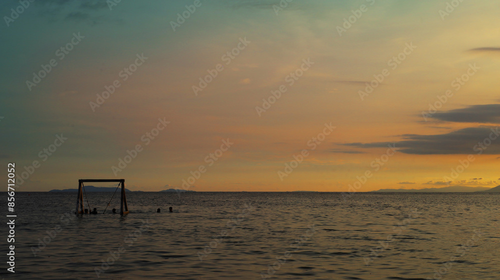 Seaside landscape featuring an ocean swing with a colorful sky Seaside landscape featuring an ocean swing with a colorful sky