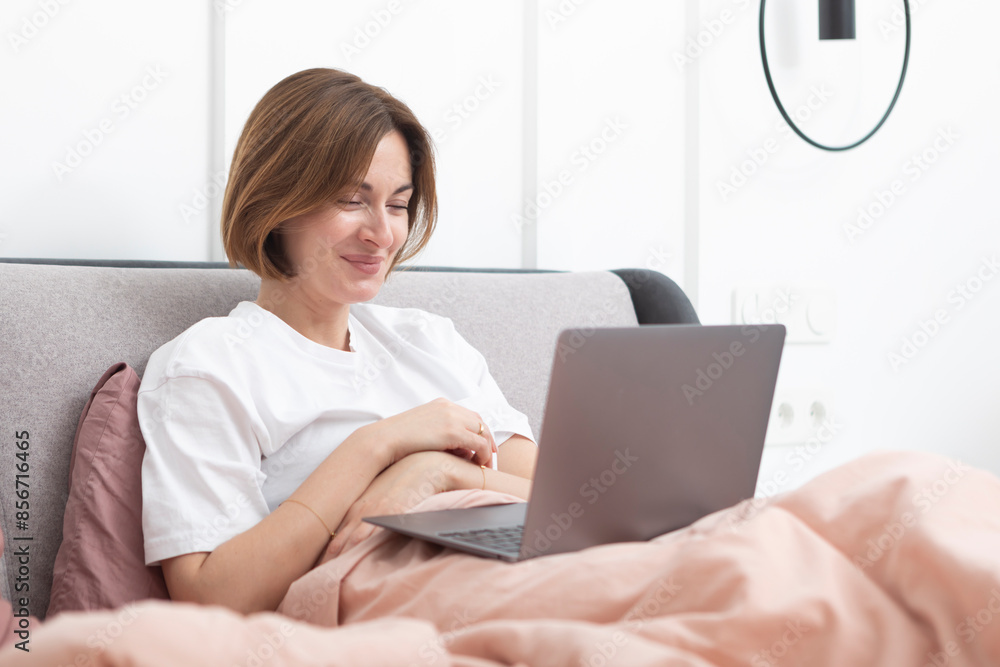 Attractive woman lying in the bed and working on laptop Attractive woman lying in the bed and working on laptop