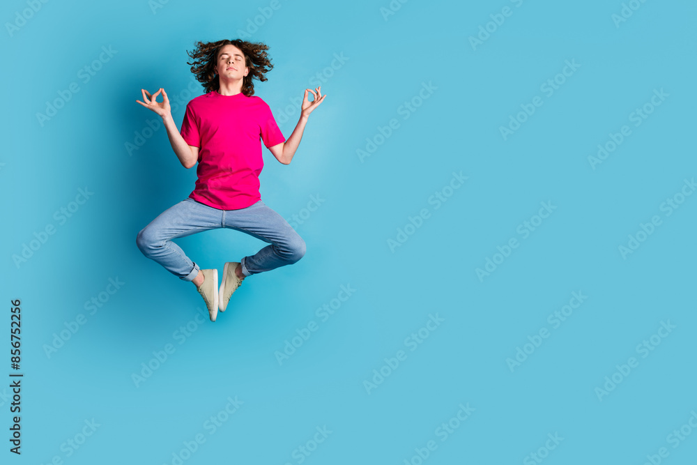 Full size photo of nice young man meditate jump wear t-shirt isolated on blue color background Full size photo of nice young man meditate jump wear t-shirt isolated on blue color background