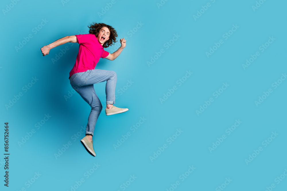 Full size photo of nice young man jump run empty space wear t-shirt isolated on blue color background Full size photo of nice young man jump run empty space wear t-shirt isolated on blue color background