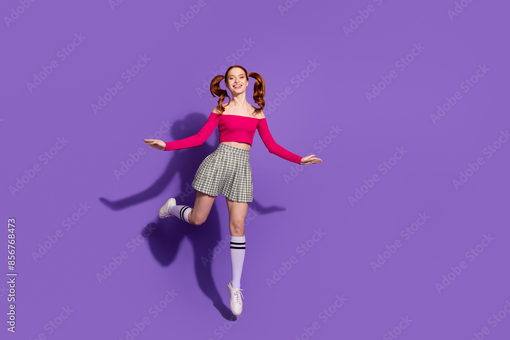 Full length photo of cheerful pretty lady dressed pink top jumping high empty space isolated violet color background Full length photo of cheerful pretty lady dressed pink top jumping high empty space isolated violet color background