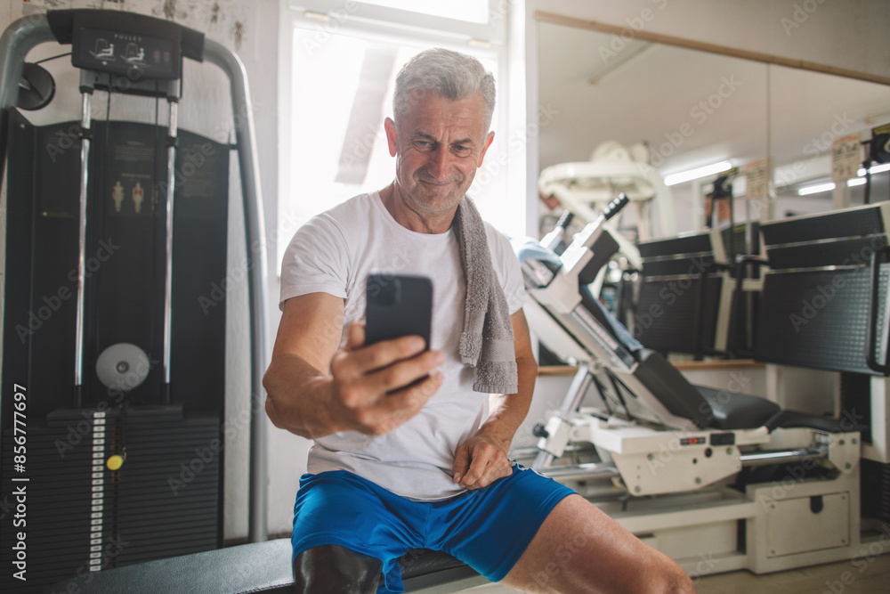 Inspiring veteran amputee using smart phone in a gym Inspiring veteran amputee using smart phone in a gym