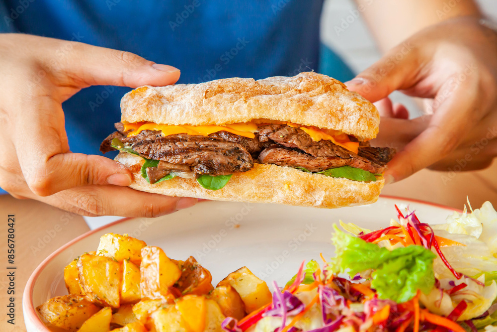 Boy holding roast beef ciabatta toasted sandwich lifestyle food in a cafe restaurant. Boy holding roast beef ciabatta toasted sandwich lifestyle food in a cafe restaurant.