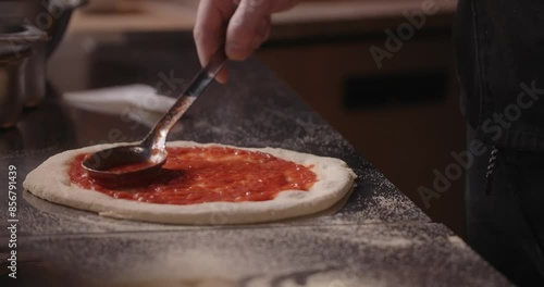 Pizza chef smears the pizza dough with tomato paste
