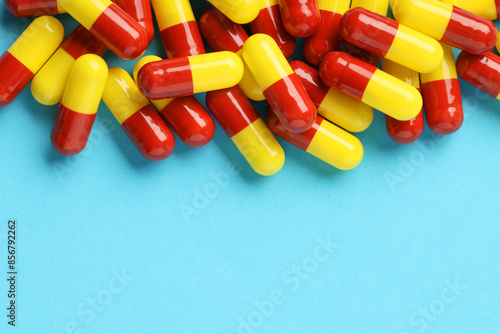 Many antibiotic pills and space for text on light blue background, top view. Medicinal treatment