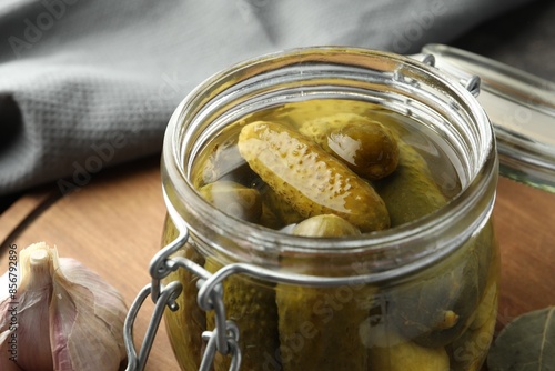 Cuadro en lienzo Pickled cucumbers in jar on wooden board, closeup