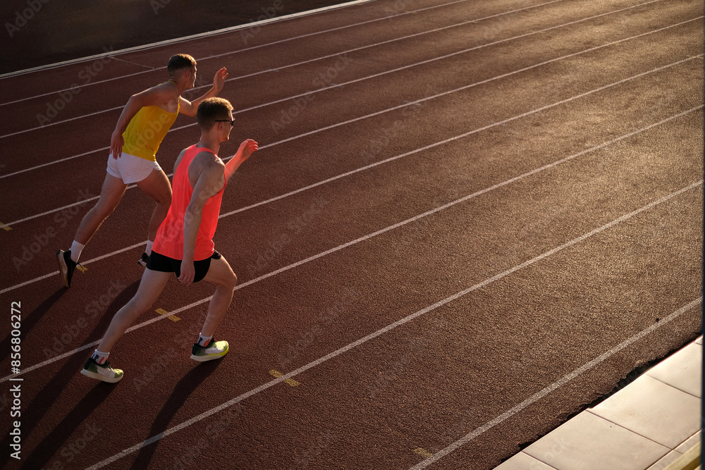 Two athletes running in a stadium at sunset Two athletes running in a stadium at sunset